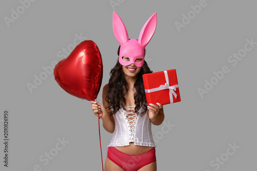 Beautiful young Asian woman in bunny mask with heart-shaped balloon and gift ...