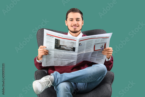 Young man reading newspaper...