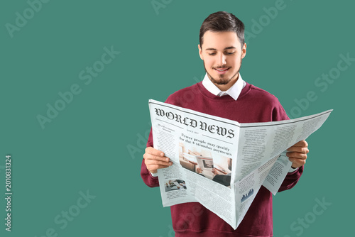 Young man reading newspaper...