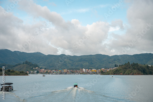 Navigating guatapé reservoir with boats and distant settlement