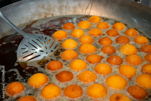 Deep-frying traditional buñuelos street food in hot oil