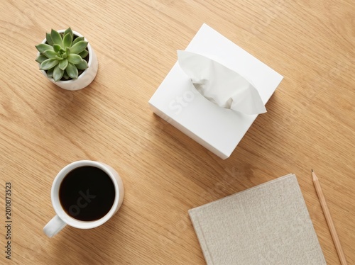 Overhead view of coffee tissues succulent and notebook on wood surface