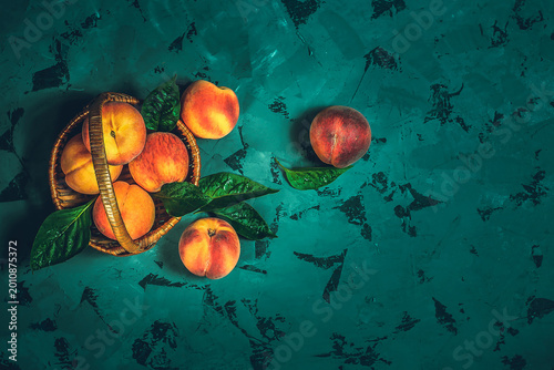 Ripe peaches in basket on a dark blue background. Top view. Copy space.