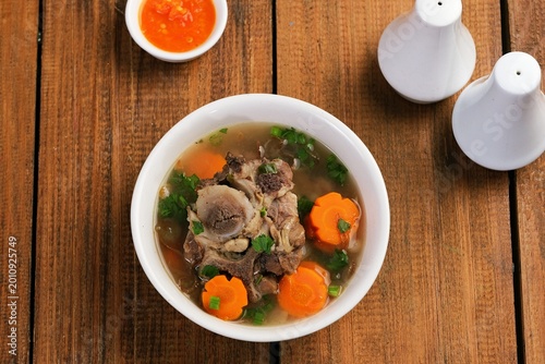 Foto Top view of oxtail soup or sop Buntut with vegetables in clean composition, highlighting traditional Indonesian dish and minimal food styling