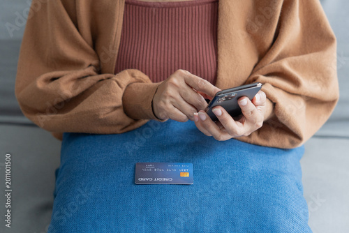 Asian mature woman using credit card booking ticket online on smartphone