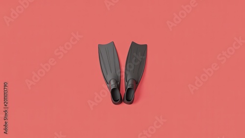 Scuba diving flippers lie on coral colored background