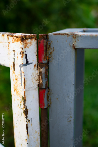 Фотография a rusty metal hinge on a crossbar that is starting to corrode