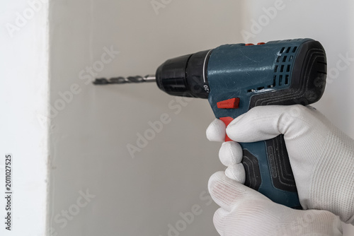 Quadro em tela Electric drill in use, applying pressure against wall surface for drilling