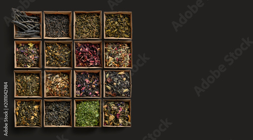 Collection of various loose tea leaves arranged on wood with vibrant petals and textured leaves