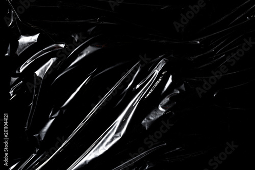 Bild auf Leinwand Transparent plastic wrap texture with wrinkles and glossy reflections on black background