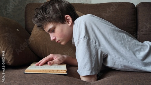 Quadro su tela Young man caucasian teenager read book study at home education concept
