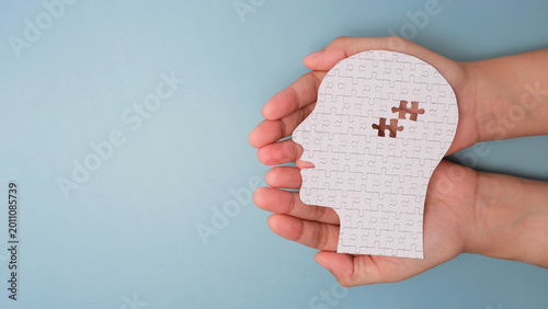 Fotografi Empathetic hand holding paper puzzle head missing piece acts as sad symbol repre