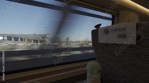 view through the window of the high speed train while moving fast through local suburb landscape natural in early morning,view from moving fast train of natural greenery landscape and mountain range