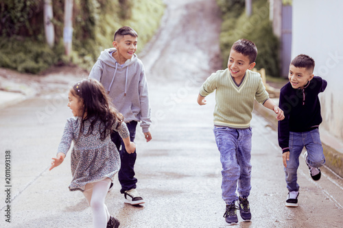 Foto Hispanic children running down the street playing and smiling