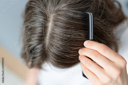 Close up of a woman whose gray hair stems from her long struggle with depression. The mature adult sees physical manifestation of mental pain in strands. Mother traces silver to suffering.