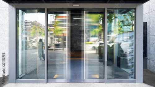 Fotografie Automatic Sliding Glass Door Entrance of Modern Building with Motion Blur in Urb