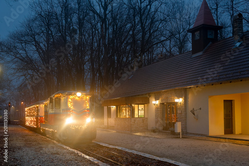 Holiday train on a platform at dusk beside station building