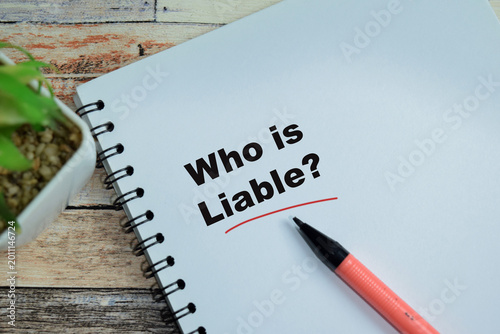 Bild auf Leinwand Concept of who is liable write on book isolated on Wooden Table