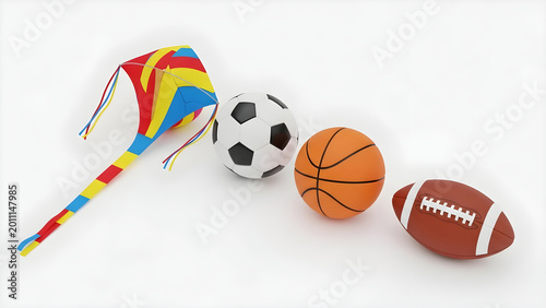 A colorful kite lies next to a soccer ball, basketball, and football on a surface.