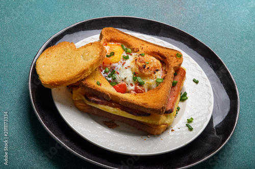 Hot breakfast sandwich with fried egg cheese and sausage. Hearty morning meal and comfort food concept for brunch or cafe menu.