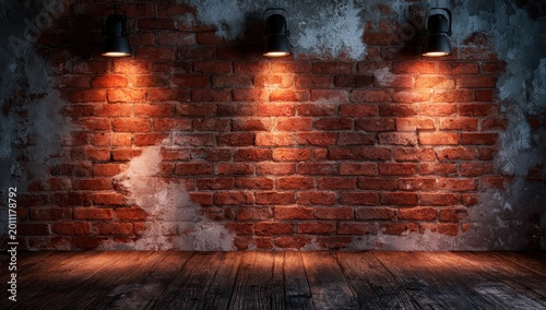Empty interior room with a rustic red brick wall background illuminated by three black industrial spotlights mounted above a dark wooden floor in a studio setting
