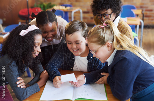 Fényképezés Students, reading and children with note in classroom, learning and smile with secret or information