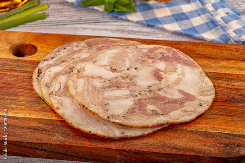 Obraz na płótnie Sliced meat roulade on wooden board with fresh vegetables and spices