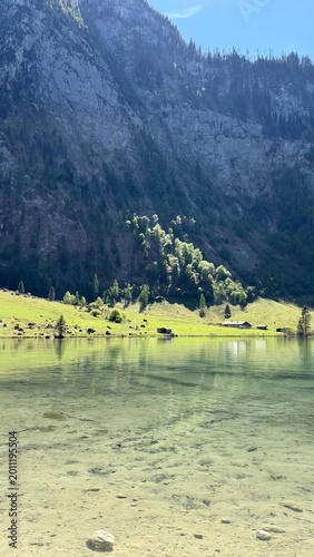 Clear Mountain Lake with Meadow Cabins and Steep Rocky Slope