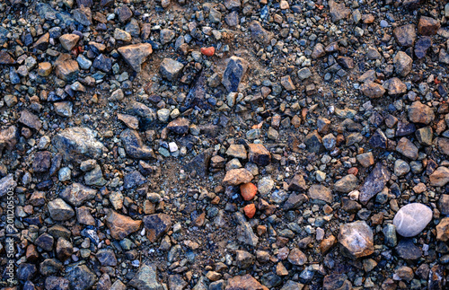 Coarse rocky ground texture featuring sharp fragmented dark gravel and dry dirt