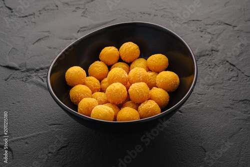 Snack balls in a black bowl on a textured surface at a kitchen table