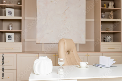 Beige leather chair, laptop and desk in office.Modern workplace.Stylish workplace with laptop, cup of coffee. elegant personal accessories in home decor.