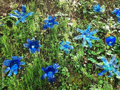 Canvas Print Decorative blue flowers made from recycled plastic bottles in grass