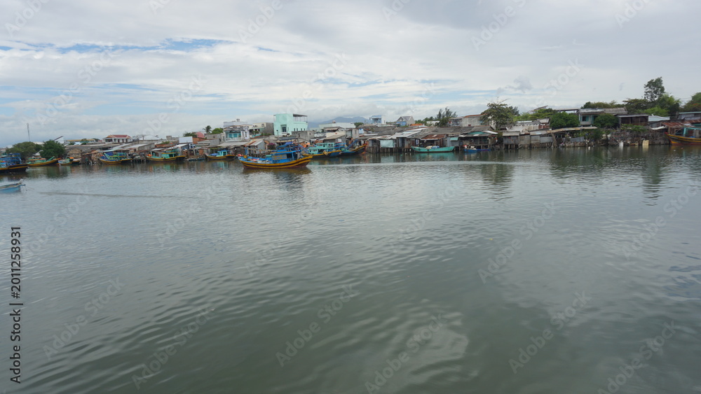 Obraz premium Riverside fishing village scenery in Binh Thuan Vietnam traditional coastal settlement boats river life local culture landscape