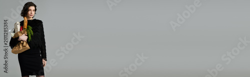 Foto Stylish young woman carries groceries on a quiet urban street in early evening l