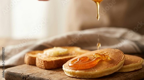 Golden Honey Drizzled Over Fresh Pancakes and Buttered Toast on a Rustic Wooden Board.