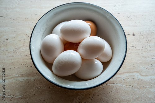 Vászonkép Shiny wet hardboiled chicken eggs gathered in simple white metal bowl resting on