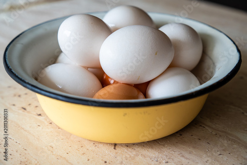 Schilderij op canvas Shiny wet hardboiled chicken eggs with white and brown shells piled inside a vin