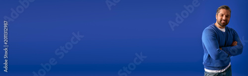 Bild auf Leinwand A stylish man confidently poses against a bright blue backdrop, showcasing moder