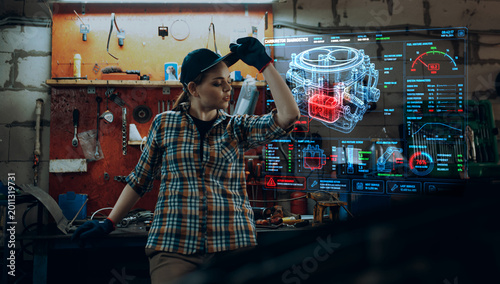 Bild auf Leinwand Female mechanic reviewing carburetor diagnostics display in auto workshop