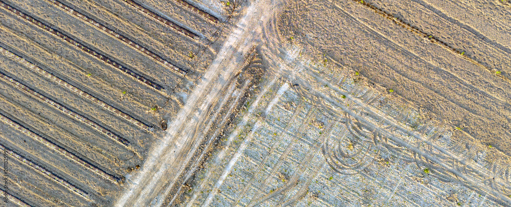 Fototapeta premium Diagonal intersection of dusty rural farm paths and plowed fields captured from above