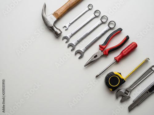 Diagonal arrangement of hand tools on white background with hammer wrenches pliers screwdriver and tape measure for banner and repair workspace layout