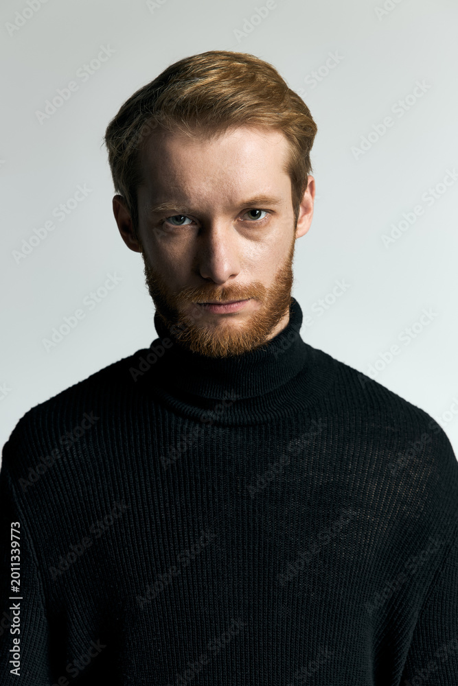 Fototapeta premium Stylish young man in a black turtleneck exudes confidence and modern fashion elegance