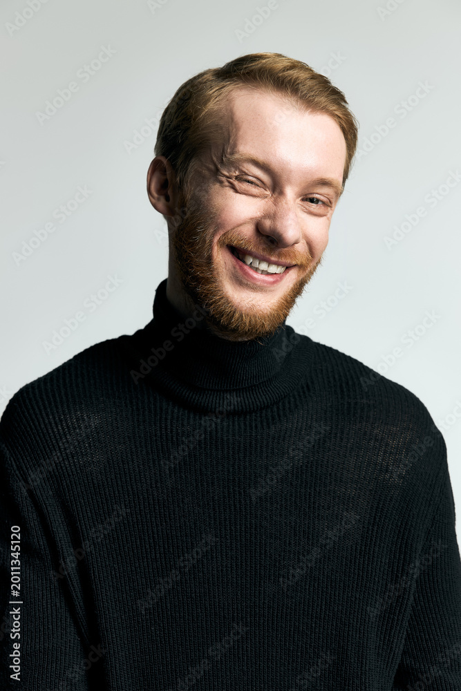 Fototapeta premium Stylish young man with a charming smile showcasing modern fashion in a minimalist setting