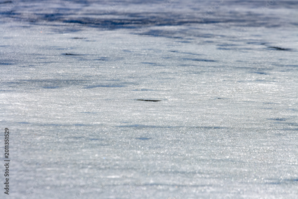 Fototapeta premium Quebec, Canada, 27 April 2026 : Close-up view of a frozen surface showing textured ice and subtle reflections under natural light.