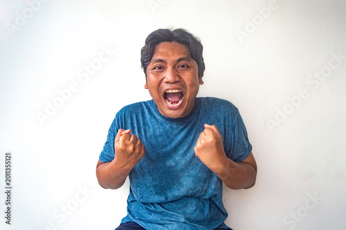 Tableau sur toile A man in a blue shirt clenches his fists in a gesture of triumph or success