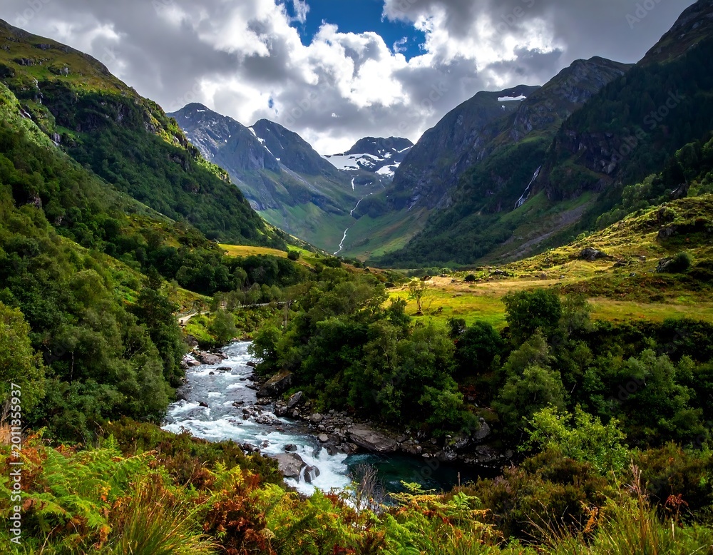 Naklejka premium River flows through a lush valley between mountainous peaks under a cloudy sky, scenic wilderness view
