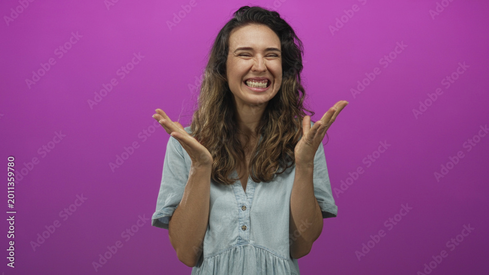 Naklejka premium Hispanic woman raises clenched fists and spreads open palms in a vibrant purple studio scene; excitement triumph celebration.