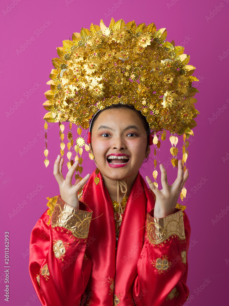 Naklejka premium Joyful Young Indonesian Asian Woman Wearing Traditional Chinese Gold Headdress And Red Silk Costume Celebrating Festival