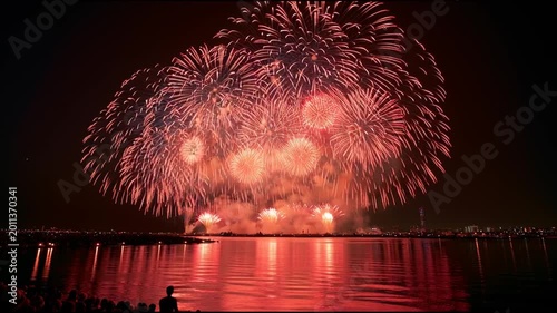 Spectacular Red Fireworks Bursting over River with City Skyline Reflection at Night