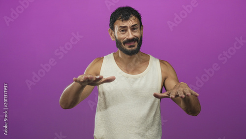 Tableau sur toile Bearded middle aged man with outstretched hands making a hesitant grimace in a purple studio; awkwardness hesitation